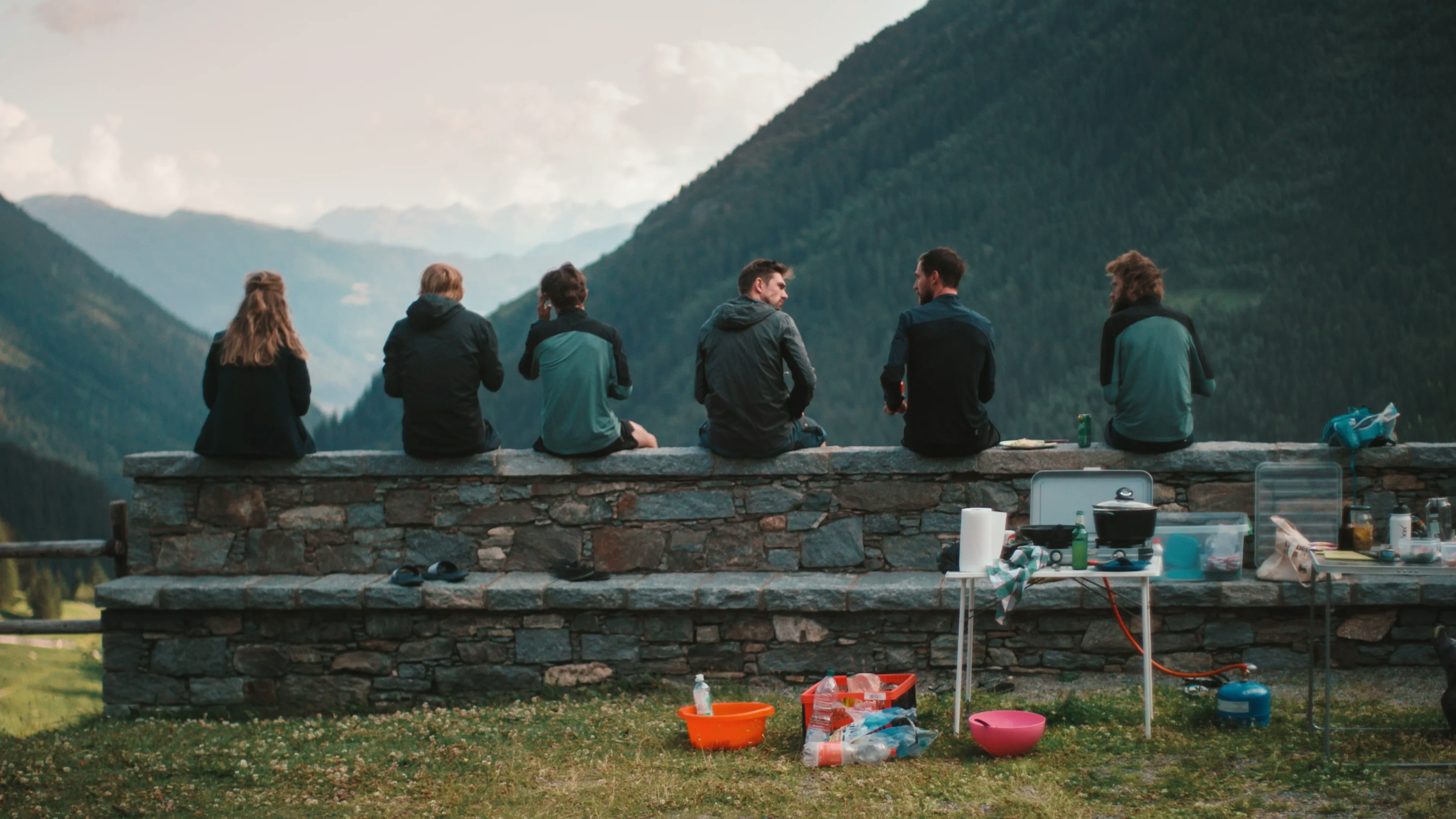 Vandrare som sitter på en tegelvägg och kollar ut över horisonten som är fylld med berg - Ny Studio