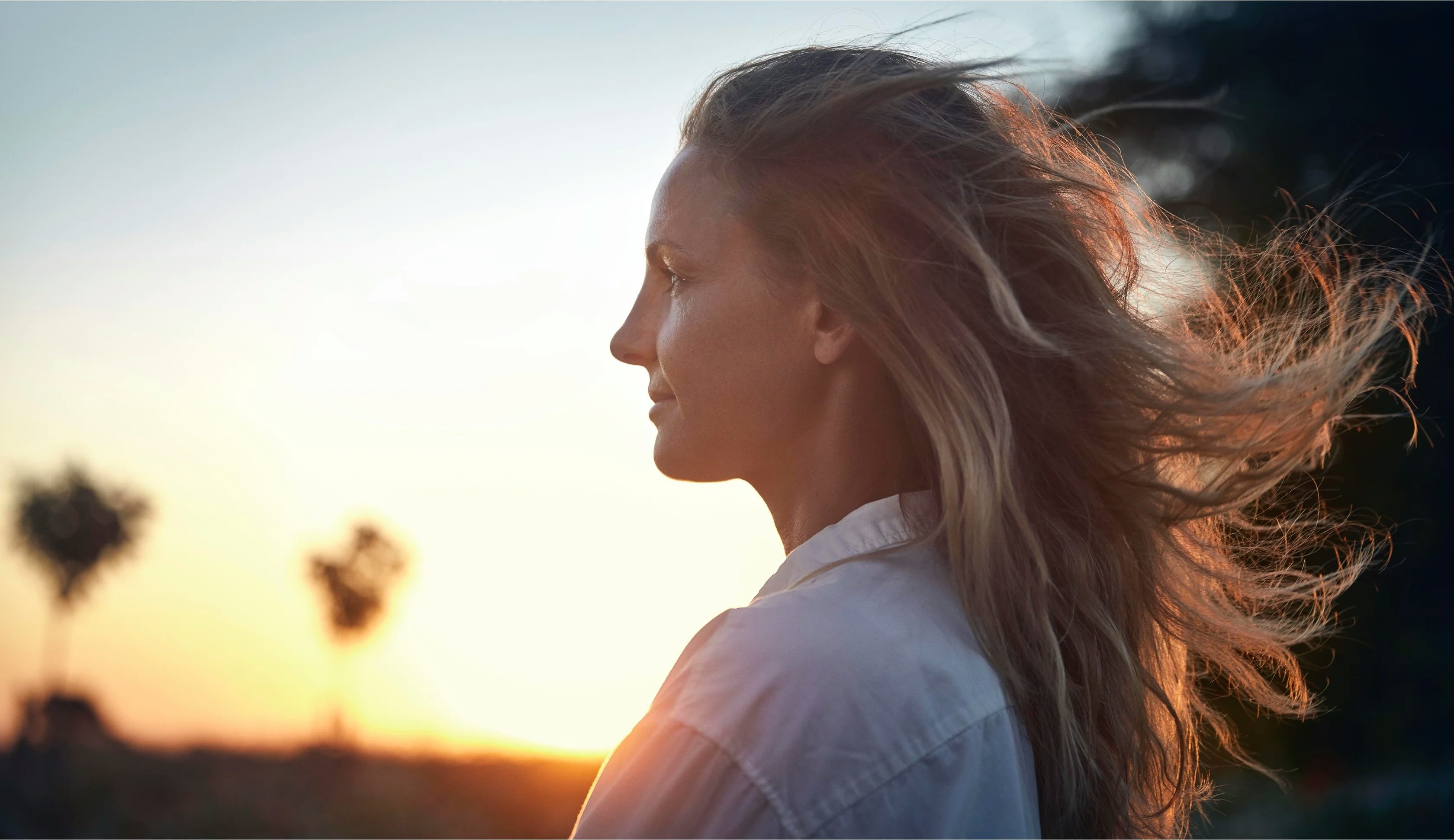 Långt blåndt hår som blåser av vinden mot en solnedgång som bakgrund - Husqvarna - NyStudio