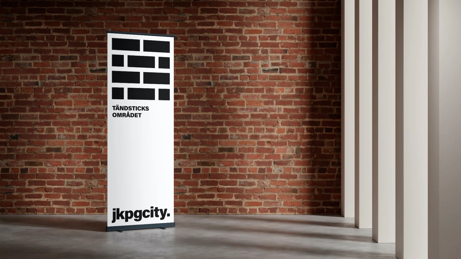 Plansch i ett rum framför en tegelstensvägg med jkpg city reklam - Ny Studio